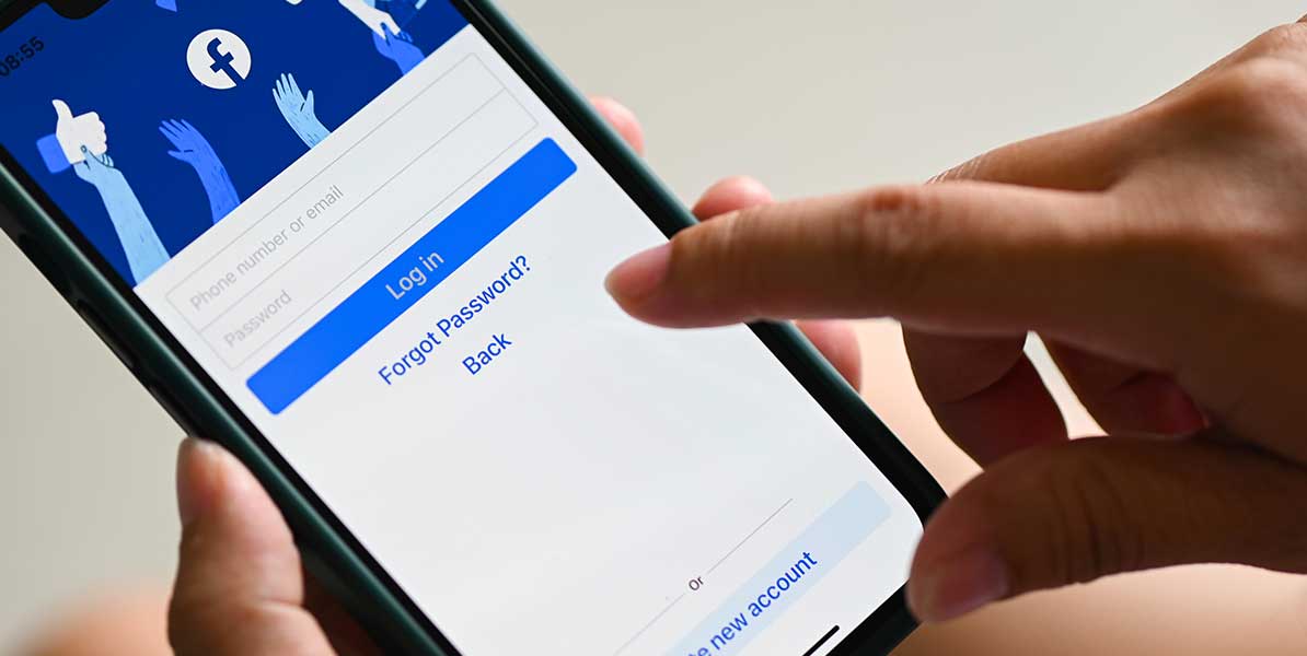Person hält Smartphone mit Login Startseite von Facebook