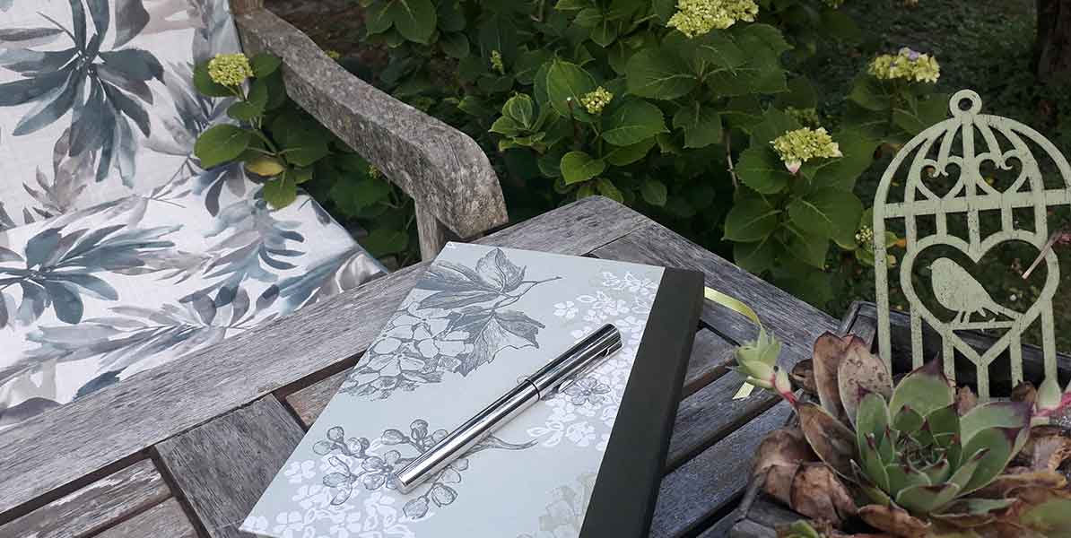 Schreibblock und Stift auf einem rustikalen Tisch im Garten